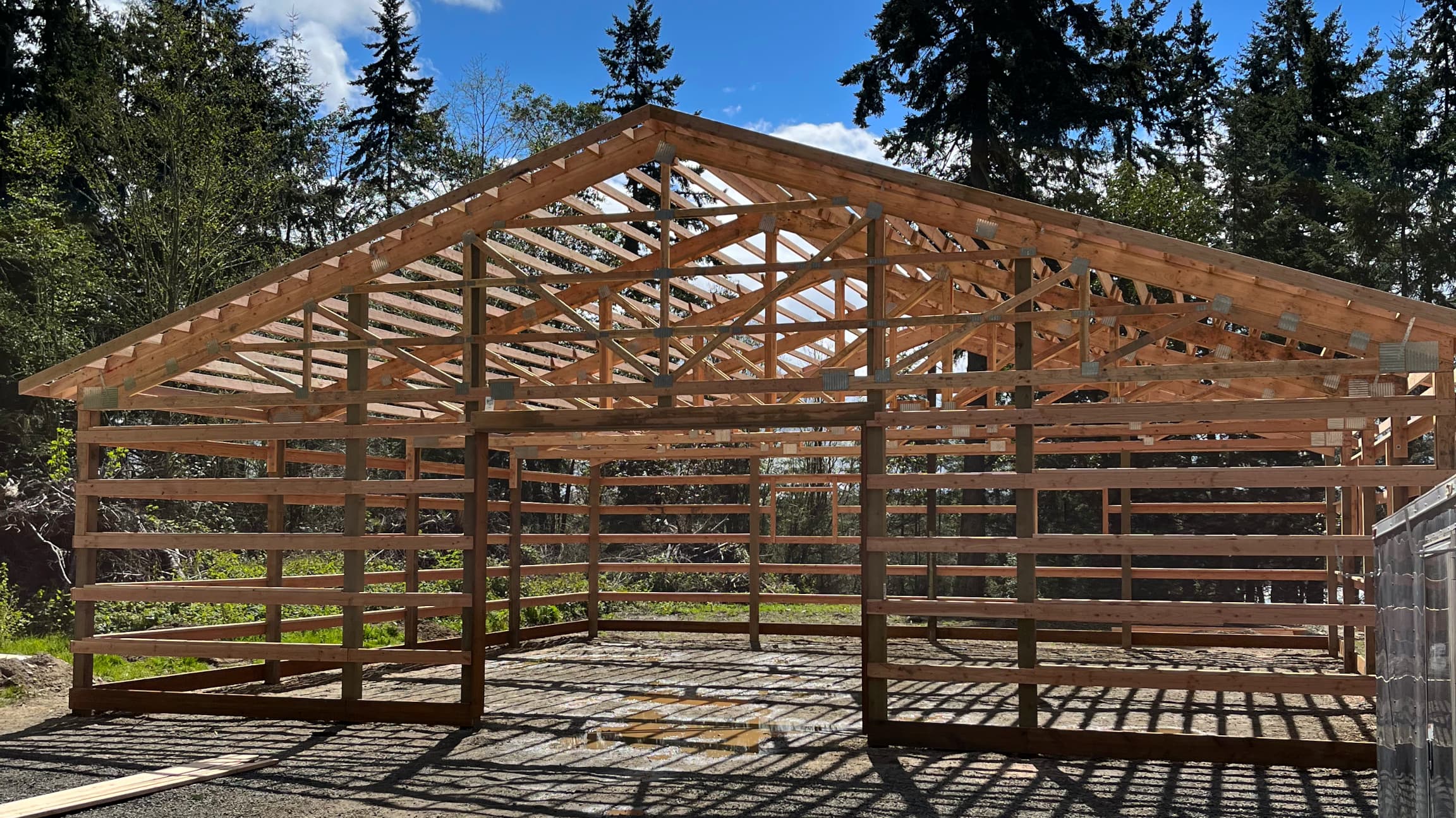 Detailed view of the completed structural framework focusing on the 10'x10' overhead door framing of this 40'x48' Probuilt metal building in Port Orchard. This professional post framing demonstrates the precision engineering that supports this 12-foot tall commercial structure designed specifically for Puget Sound weather conditions.
