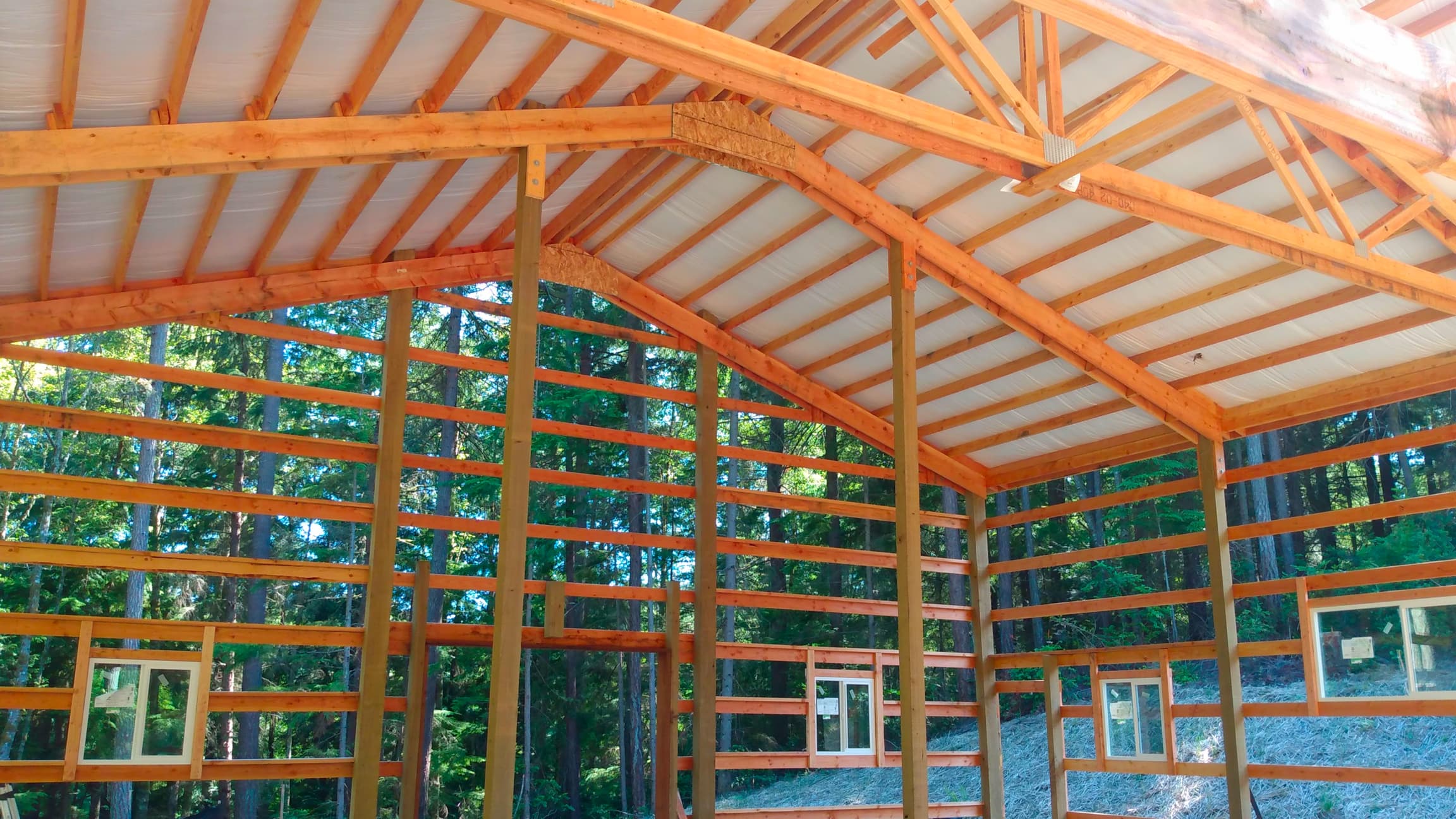 Interior view of a 36'x36' Probuilt Metal building in Olalla showing completed roof installation with insulation. This 16' tall structure features engineered trusses and extensive wood framing for superior durability in Pacific Northwest conditions.